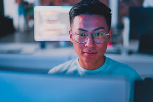 A man with glasses working at a computer