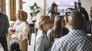 Small, diverse groups of people sitting at round tables