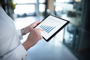 A woman holding a tablet with a bar chart on it