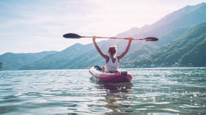 A woman in a canoe holding the paddle over her head