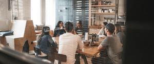 A group of colleagues sitting at a table in an office common area