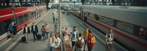 A busy European train station platform with passengers and soccer fans gathered between two trains.
